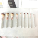 Lifestyle image of brushes laid out beside compact powder and lipstick on vanity