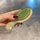 Side view showing ergonomic S-curve handle and diamond-accented top on yellow-and-green hairbrush