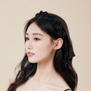 Black pleated headband styled on model with low bun, highlighting crown lift effect