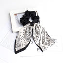 Black cashew print satin scrunchie on white surface close-up